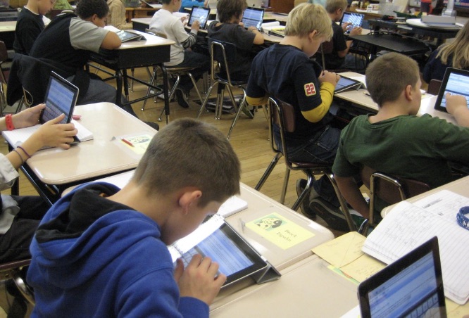 A classroom of elementary students working on individual tablets at their desks